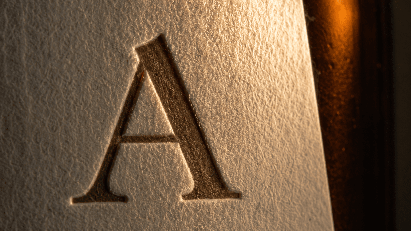 Debossed Roman A — the brand signature across every touchpoint.